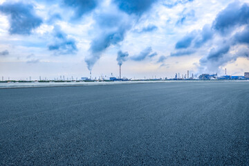 Asphalt road with industrial plant and smoking chimneys background