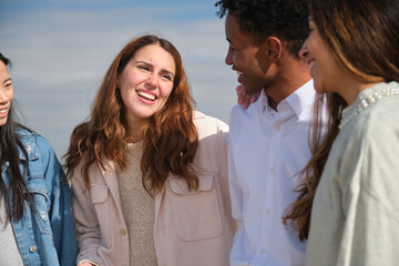 Four colleagues sharing a laugh during a casual outdoor meeting, showcasing teamwork and camaraderie