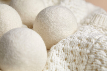Close-up of white wool dryer balls nestled on a textured knitted blanket, creating a soft and cozy ambiance. Highlights sustainable, eco-friendly laundry essentials