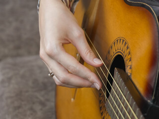 Close-up of a musician's hand delicately adjusting the tuning of acoustic guitar strings, ensuring...