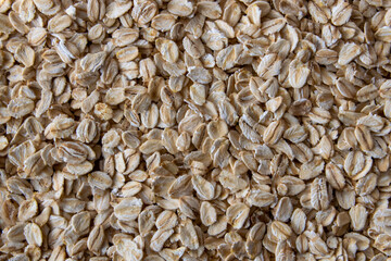 Uncooked dry oat flakes background on the table.