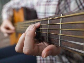 Close-up view of a musician's hands skillfully playing chords on the fretboard of an acoustic...