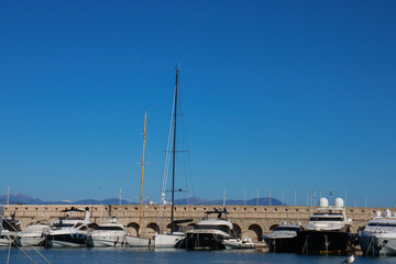 Luxury yachts docked in French riviera old fort marina under a clear sky.