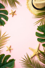 Palm leaves, sea shells, hat and sunglasses on pink background.