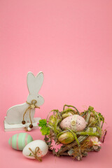 Easter eggs in a wicker nest on a pink background. Easter eggs and a bunny