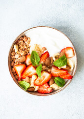 Yogurt with granola and strawberries on white.