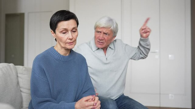 Angry furious abusive husband yelling, gesturing aggressively at scared sad silent wife. Woman near tears, domestic violence victim, gaslighting toxic relationship, emotional abuse, family conflict