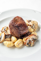 A delicious plate of tender beef fillet served on a bed of creamy gnocchi and sautéed mushrooms, garnished for an elegant culinary presentation.