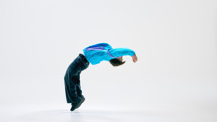Dynamic photo of freestyle dancer mid-flip, arms extended against white background, movement caught in flight. Concept of physical excellence, motion artistry, urban sports, expression through dance