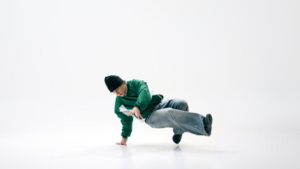 Breakdancer in fluid motion with legs kicking sideways while maintaining control against white studio background. Concept of sport, rhythm, dance, energy, street performance.