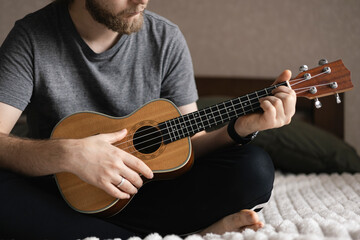 Obraz premium Man learns to play the ukulele. The concept of online learning, home education.