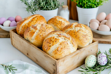 Golden homemade bread with a crispy crust in a rustic wooden tray, surrounded by pastel Easter eggs, fresh rosemary, and kitchen greenery for a festive spring setting