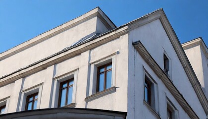 A white, minimalist building stands against a bright blue sky. Clean lines and subtle textures highlight its modern aesthetic, capturing a serene, architectural moment in urban design and airy charm