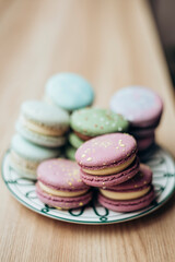 Pastel colored macaroons on a plate on a wooden table, close-up.