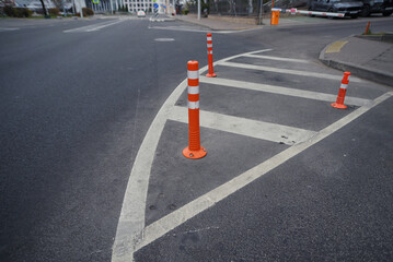 Urban road infrastructure with safety cones and clear street markings, cones in front of the entrance and exit to the building prohibiting parking for cars ensuring traffic safety in cityscape setting