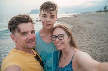 Fototapeta premium Happy family taking a photo on a beach at the sea in Alanya city, Turkey. Travelling or vacation concept