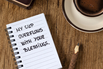 Inspirational handwritten quote for God's blessings and generosity with cup of coffee and holy bible on wooden table. Top view. Christian biblical concept.