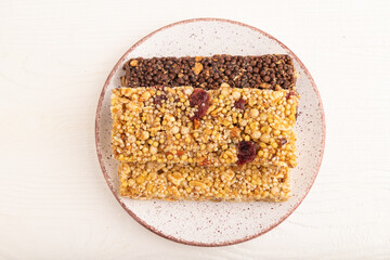 granola bars with caramel, nuts, flakes in ceramic plate on white wooden. Top view, close up.
