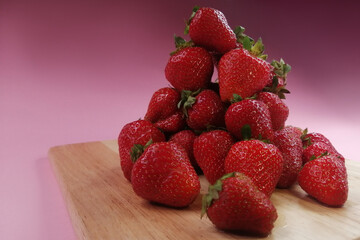 a mountain of strawberries on a pink background