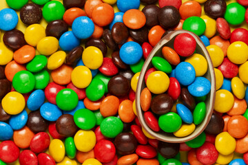 Multicolored dragee with chocolate egg, Easter, candy background, sweets