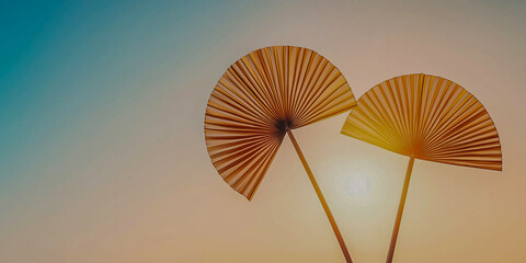 Two decorative fans silhouetted against a colorful sunset, creating a serene and artistic atmosphere.