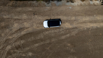 White electric car driving on dirt road, White electric car vehicle passing through dirt road, White electric vehicle car offroad 4wd, 4x4 off road ev car. © Kalyakan