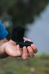 Close up of man hands holding engagement ring box on the beach