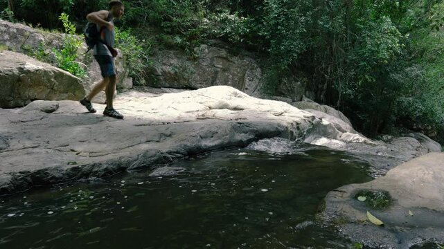 A tourist sits down next to a mountain stream for a rest and gets food