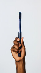 Dark-toned hand holding a dark blue toothbrush against a white background.
