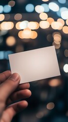 Blank card held in hand against a backdrop of glowing lights