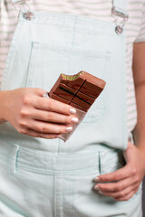 Dubai chocolate bar with filling made of kataifi (knafeh, kadayif) and pistachio  paste. Trendy food. Bitten chocolate bar in women's hands.