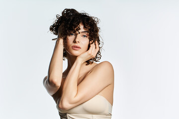 Obraz premium A beautiful young woman exudes grace in a pose against a light background.