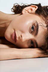 Radiant young woman rests her head on her arm, showcasing natural beauty and grace.