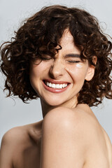 Young woman with curly hair beams with happiness while highlighting her natural beauty.