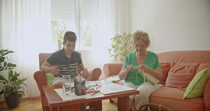A heartwarming scene of a grandmother knitting while her grandson draws, showcasing family bonding and inter generational connection.
