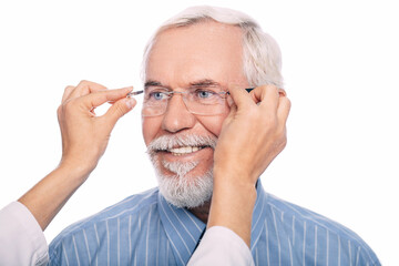 Fototapeta premium Elderly man smiles as technician adjusts his new glasses in a modern ophthalmology clinic, showcasing personalized patient care