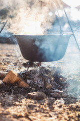 Rustic Cooking Scene with Hanging Cast Iron Pot Over Fire Pit in Outdoor Setting