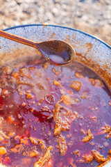 Cooking Traditional Stew in a Rustic Pot with Wooden Spoon Outdoors