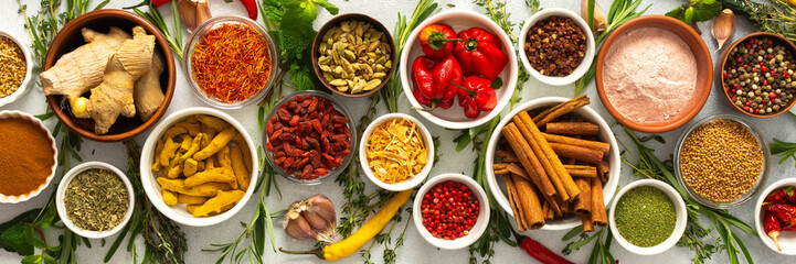 Assorted cooking spices and herbs arranged on a gray surface, featuring natural tones that add depth and aroma to any meal, banner