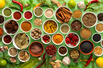A colorful assortment of fresh, fragrant spices and herbs displayed on a soft green background, capturing a vibrant culinary essence