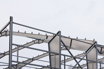 Metal construction, in the photo the structure of the building frame made of metal beams against the background of a gray sky