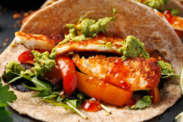 Fried halloumi fajitas with pan roasted onions and bell peppers, avocado guacamole and pickled jalapeno peppers