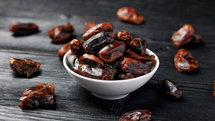 Dried sweet pitted dates in white bowl. Healthy food