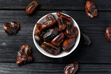 Dried sweet pitted dates in white bowl. Healthy food