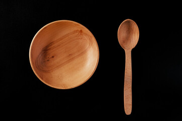 Eco-friendly cutlery made of wood. Spoon and plate on a black background