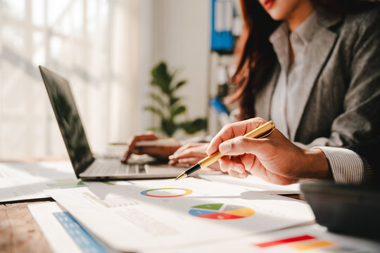 Junior colleagues meet to discuss business charts and analytical investment budgets using calculators and laptops to calculate financial, tax, accounting, statistics, and analytical research ideas.
