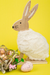 Nest with Easter eggs and a rabbit on a yellow background. Easter eggs