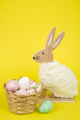 Nest with Easter eggs and a rabbit on a yellow background. Easter eggs