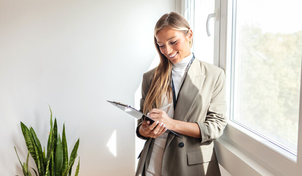 Portrait, checklist and business woman in office happy, smile and confident with positive mindset. Leader, face and female corporate employee with clipboard for management, schedule and agenda.