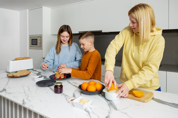A mother and her two children making a healthy breakfast together, sharing family tasks